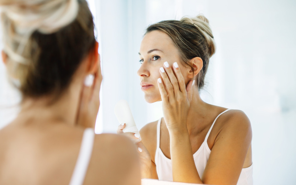 Frau cremt sich während eines Langstreckenfluges das Gesicht vor dem Spiegel ein