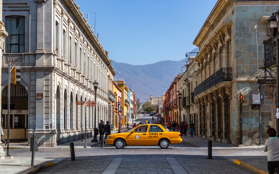 Ein gelbes Taxi fährt durch die Straße in der Nähe der Hauptstraße in Oaxaca de Juárez, Mexiko.
