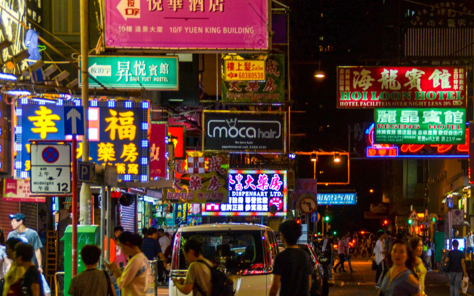 Beleuchtete Stra&szlig;e in Hongkong bei Nacht mit vielen bunten Schildern