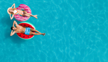 Ein Mann und eine Frau lassen sich auf einem Schwimmreifen im Pool treiben